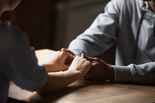 Photo of two people clasping hands, representing support for someone impacted by the Opioid crisis.